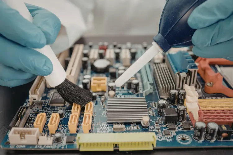 Technician applying thermal compound and cleaning motherboard components for heatsink cooling and thermal management