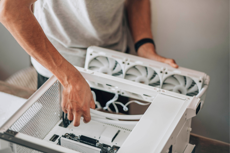 Person installing a cooling fan assembly inside an electronic enclosure for thermal management.